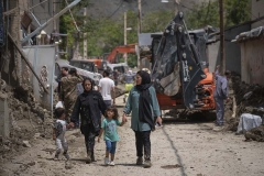 NPNW27JUL3122. An Iranian family walk along a street which is covered with mud as they look at destroyed buildings in the flooded village of Mazdaran in Firoozkooh county 124 km (77 miles) northeast of Tehran, after flash flooding, July 31, 2022.
