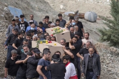 NPNW41AUG0322. Iranian villagers carrying the coffins containing the bodies of victims of a sudden-flood, at a graveyard during a funeral in the flooded village of Mazdaran in Firoozkooh county 124 km (77 miles) northeast of Tehran, August 3, 2022.