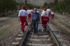 NPNW44AUG0222. Members of the Iranian Red Crescent Society (IRCC) walk along a railway in the flooded village of Mazdaran in Firoozkooh county 124 km (77 miles) northeast of Tehran, as a villager walks to a train station for leaving flooded area to a safer place, four days after flash flooding, August 2, 2022.
